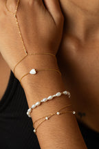 Bracelet Cœur nacre porté en accumulation avec d'autres bracelets dorés