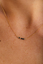 Collier court Théa porté, enfilage de spinelles au creux du cou, or laminé 585/1000