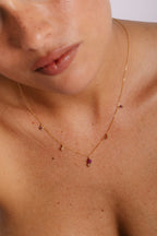 Collier Gaia rubis porté au creux du décolleté, grelots fixes sur la chaîne