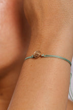 Bracelet cordon Rosa vert porté au poignet, rose en or laminé