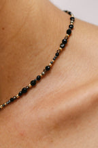 Collier Vénus Minuit porté, enfilage de pierres sombres au creux du cou