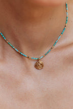 Pendentif Rosa moyen porté sur un collier de pierres turquoise