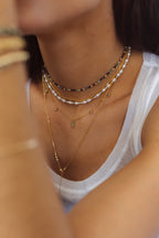 Collier Grain de riz porté en superposition avec d'autres chaînes dorées