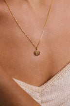 Petit pendentif Rosa porté au creux du cou sur une chaîne fine